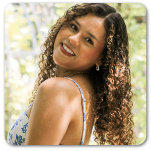 Heydi posing outdoors with a smile and a blue and white dress